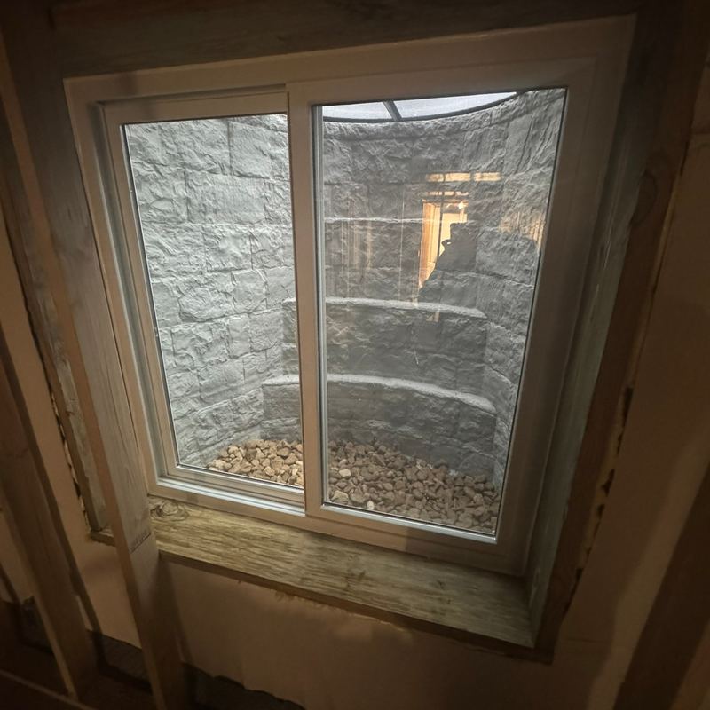 A new egress window with a stone window well outside it