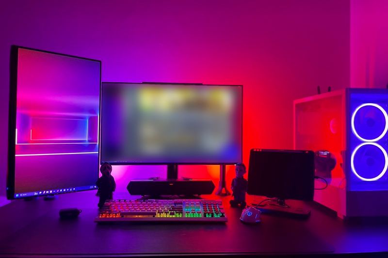 The computer back together and running on a desk, its front fans lit, beside the monitors