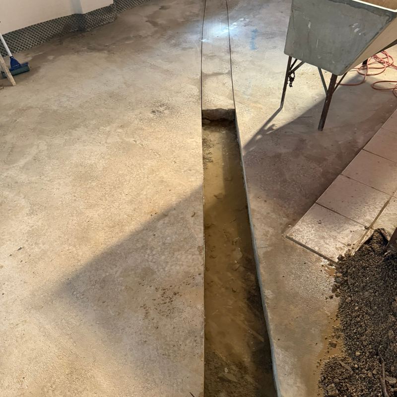 A trench cut into the concrete basement floor